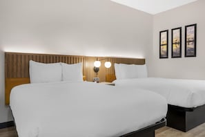 A hotel room with two beds, a wooden headboard, a wall-mounted lamp, and three framed pictures. - Best Western San Diego Pacific Beach/mission Bay (San Diego)