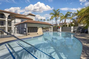 A swimming pool with a tiled edge, a covered area with a roof, and palm trees in the background. - Best Western San Diego Pacific Beach/mission Bay (San Diego)