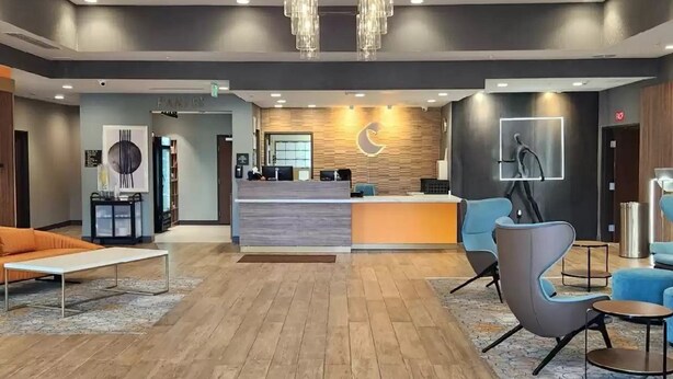 A modern hotel lobby with a reception desk, seating area, and a large chandelier. - Comfort Suites Cheyenne, WY (Cheyenne)