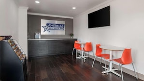 A reception area with a sign for 'AMERICAS Best Value Inn', a counter, and seating with orange chairs. - Americas Best Value Inn Orlando (Orlando)