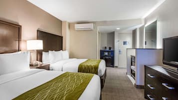 A hotel room with two beds, a TV, a dresser, and a bathroom visible through an open door.