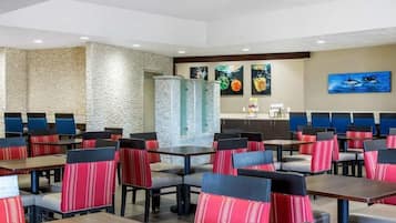 A restaurant with booths and tables, a stone wall, and artwork on the walls.