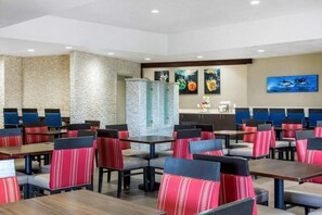 A restaurant with booths and tables, a stone wall, and artwork on the walls. - Best Western Inn & Suites San Diego - Zoo/seaworld Area (San Diego)