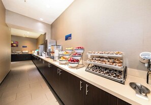 Un espace dédié au petit-déjeuner à l’hôtel, aménagé en buffet, avec une variété de plats et un coin café.