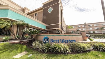 Un hôtel avec une enseigne indiquant « Best Western » et une entrée aménagée avec des palmiers.