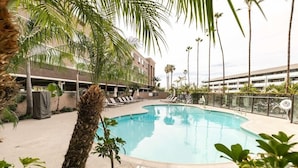 A swimming pool surrounded by palm trees and lounge chairs, with a building in the background. - Best Western Inn & Suites San Diego - Zoo/seaworld Area (San Diego)