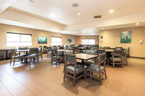 A spacious dining area with multiple tables and chairs, large windows, and artwork on the walls. - Best Western Inn & Suites San Diego - Zoo/seaworld Area (San Diego)