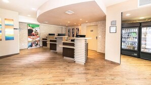 A reception area with a counter, a refrigerator stocked with beverages, and a wall with a poster. - Best Western Inn & Suites San Diego - Zoo/seaworld Area (San Diego)