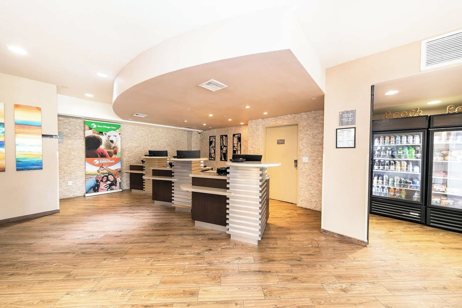 A reception area with a counter, a refrigerator stocked with beverages, and a wall with a poster.