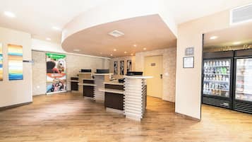 A reception area with a counter, a refrigerator stocked with beverages, and a wall with a poster.