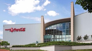 A modern building with a Coca-Cola sign, featuring a curved glass facade and a flat roof. - Motel6 Atlanta, GA - Atlanta Airport East (Atlanta)
