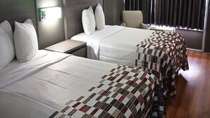 Une chambre d’hôtel avec deux lits, une table de chevet, une chaise et une fenêtre avec des rideaux.