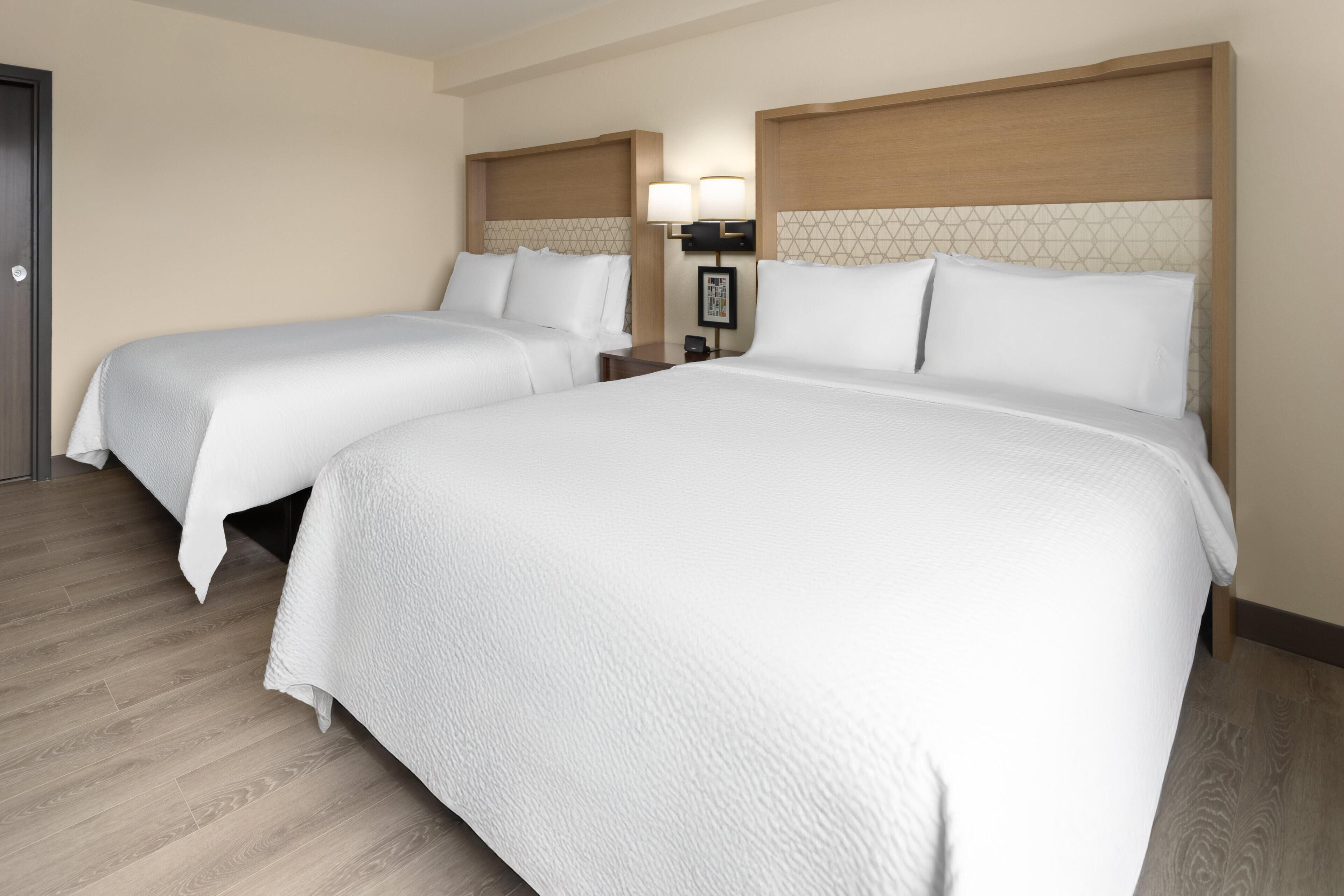 Ein Hotelzimmer mit zwei Betten, einem Nachttisch mit Lampe und einer Tür.
