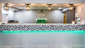 A reception desk with a mosaic tile design, a green illuminated display, and three hanging lantern-style lights. - Rest and Relax Inn (Pensacola)
