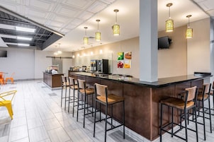 Una cocina moderna con una isla central, taburetes de bar e iluminación colgante.
