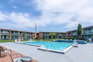A swimming pool with a 3 ft depth marker, surrounded by a brick patio with outdoor seating.