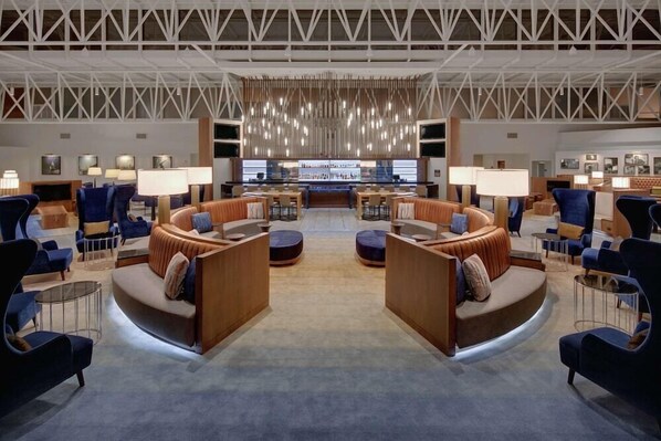 A spacious lobby with a central seating area, a bar, and a high ceiling with a geometric design. - Nashville Airport Marriott (Nashville)