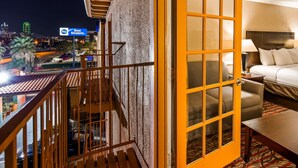 A hotel room with a balcony, a bed, a desk, and a view of the cityscape. - Motel6 Dallas, TX - Downtown (Dallas)