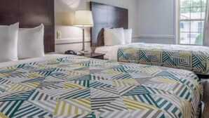A hotel room with two beds, a nightstand, a lamp, and a window with a view. - Motel6 Dallas, TX - Downtown (Dallas)