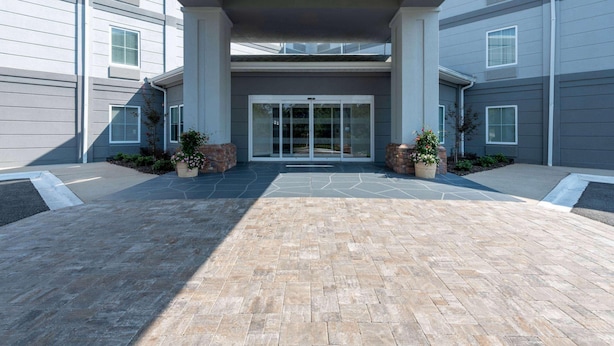 A building entrance with a paved area, large columns, and a glass door. - Tryp by Wyndham Tallahassee North I-10 Capital Cir (Tallahassee)