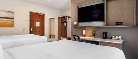 A hotel room with two beds, a desk with a chair, a television, and a coffee maker.
