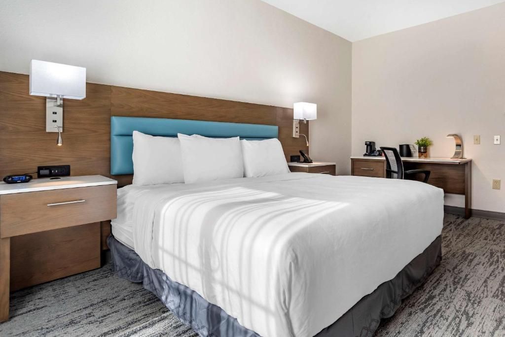 Een hotelkamer met een groot bed, nachtkastjes, een bureau met stoel en een lamp.