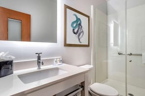 A bathroom with a white sink, a mirror, a framed abstract painting, and a glass shower enclosure. - Tryp by Wyndham Tallahassee North I-10 Capital Cir (Tallahassee)