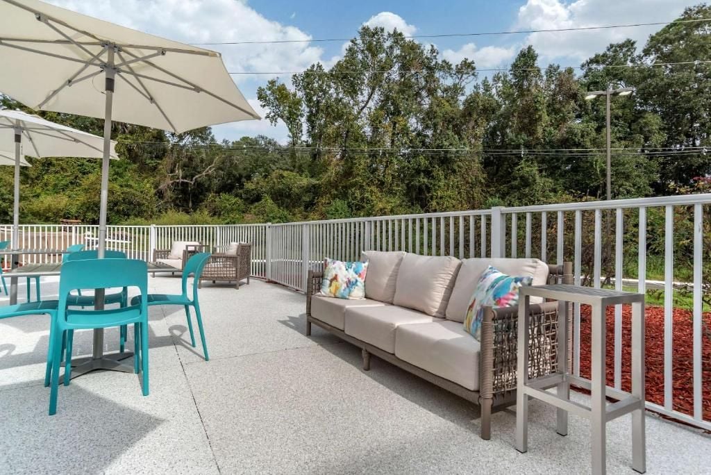 An outdoor patio with a sofa, chairs, and a table under a large umbrella.