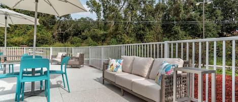 An outdoor patio with a sofa, chairs, and a table under a large umbrella.