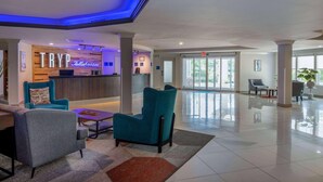 A lobby with teal chairs, a reception desk, and a large window. - Tryp by Wyndham Tallahassee North I-10 Capital Cir (Tallahassee)