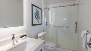 A modern bathroom with a glass-enclosed shower, a white sink with a mirror, and a toilet. - Tryp by Wyndham Tallahassee North I-10 Capital Cir (Tallahassee)