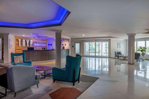 A lobby with teal chairs, a reception desk, and a large window. - Tryp by Wyndham Tallahassee North I-10 Capital Cir (Tallahassee)