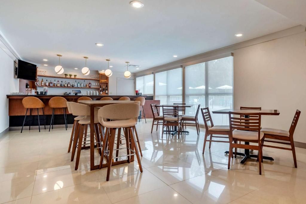 A modern bar area with a counter, stools, and hanging pendant lights.