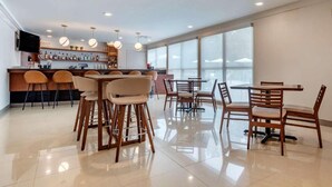 A modern bar area with a counter, stools, and hanging pendant lights. - Tryp by Wyndham Tallahassee North I-10 Capital Cir (Tallahassee)