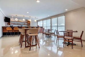 A modern bar area with a counter, stools, and hanging pendant lights. - Tryp by Wyndham Tallahassee North I-10 Capital Cir (Tallahassee)