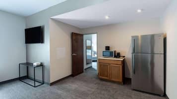 A compact kitchen with a refrigerator, microwave, and a small table.