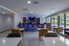 A modern restaurant with a bar area, seating arrangement, and large windows. - Tryp by Wyndham Tallahassee North I-10 Capital Cir (Tallahassee)