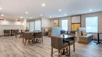 A modern hotel room with a dining area, seating arrangements, and artwork on the walls.