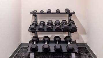 A wall-mounted dumbbell rack with multiple sets of weights.