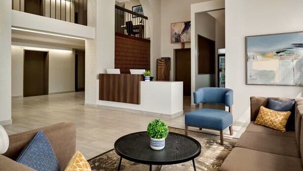 A spacious lobby with a reception desk, seating area, and a staircase. - Wingate by Wyndham Williamsburg (Williamsburg)