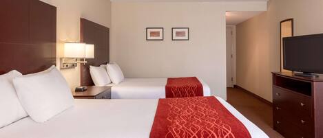 A hotel room with two beds, a TV, a dresser, and two framed pictures on the wall.