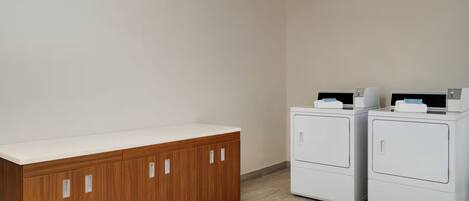 A laundry room with a wooden cabinet and two stacked washing machines.