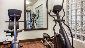 Une salle de sport équipée de deux vélos d’exercice, d’un miroir et d’un mur sur lequel est accrochée une horloge.