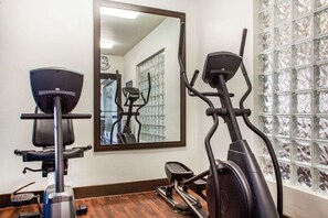 A gym with two exercise bikes, a mirror, and a wall with a clock. - Fairfield Inn & Suites by Marriott Scottsdale Old Town (Scottsdale)