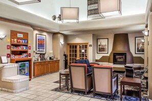 A hotel lobby with a seating area, a kitchenette, a refrigerator stocked with snacks, and a fireplace. - Fairfield Inn & Suites by Marriott Scottsdale Old Town (Scottsdale)