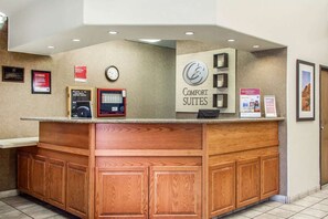 A reception desk with a sign for 'Comfort Suites,' a clock, and informational posters. - Fairfield Inn & Suites by Marriott Scottsdale Old Town (Scottsdale)