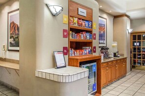 Een hotel receptie met een snackbar, een koelkast en een koffiehoek.