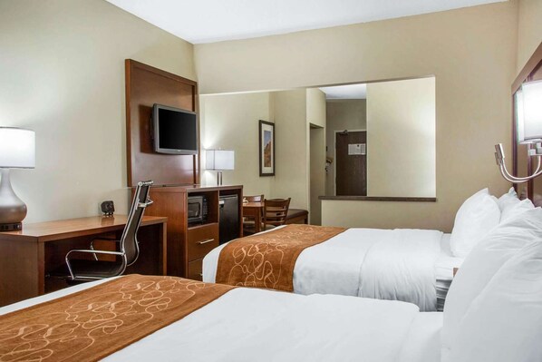 Une chambre d’hôtel avec deux lits, un bureau, une télévision, une chaise, un four à micro-ondes et un miroir.