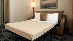 A neatly made bed with a beige bedspread and two pillows, a standing lamp, and a framed picture on the wall. - Fairfield Inn & Suites by Marriott Scottsdale Old Town (Scottsdale)
