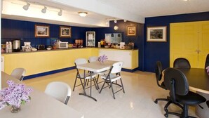A room with a yellow counter, white chairs, a table with a vase of flowers, and a black office chair. - Evergreen Studios (Sheridan)